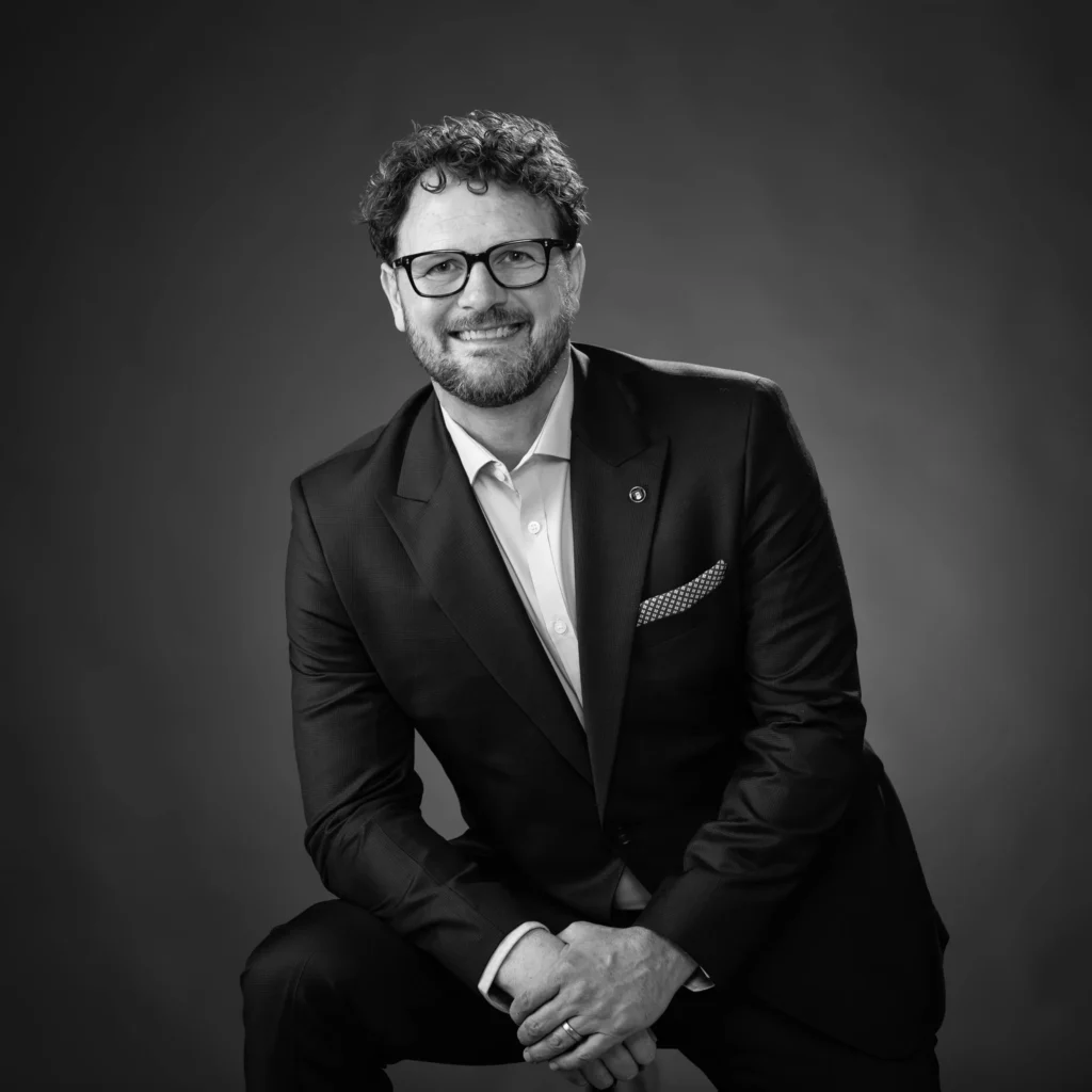 A man wearing a suit smiles for the camera.